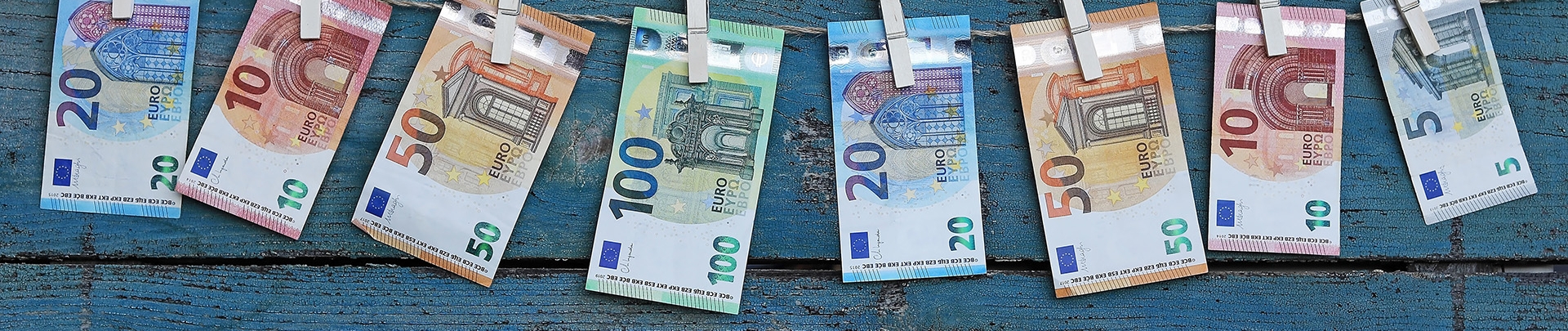 Verschillende euro biljetten hangen aan een waslijn met wasknijpers